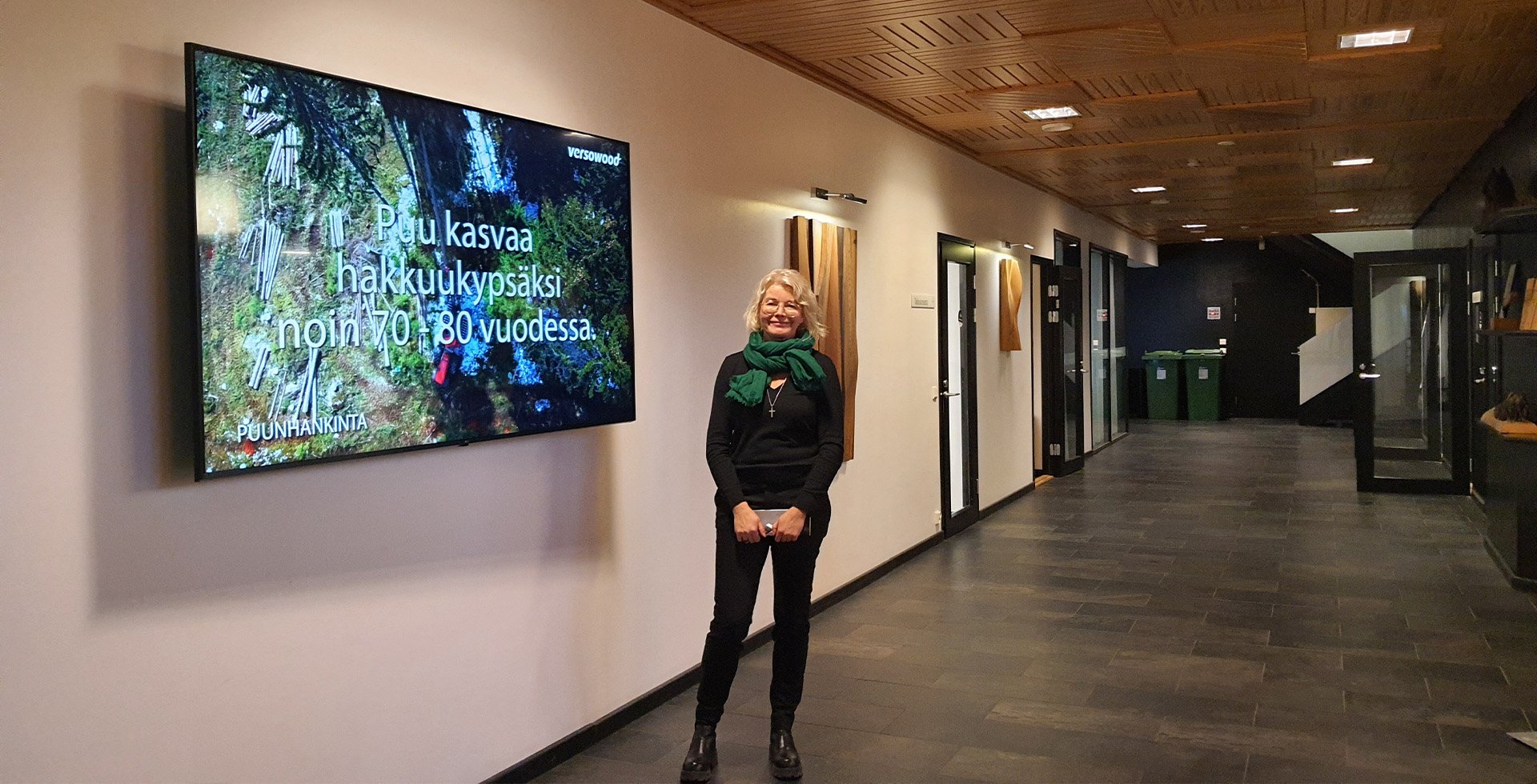 Mia Kärkkäinen Versowoodin suuren brändinäytön vieressä
